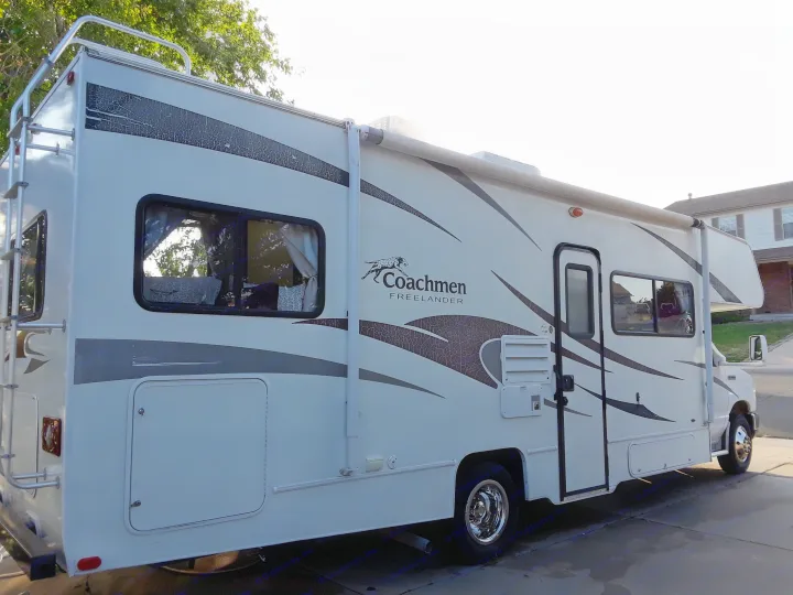 A white Coachmen Freelander RV rental with black/grey graphics and a rear ladder, perfect for road trips.. Coachmen Freelander 2011