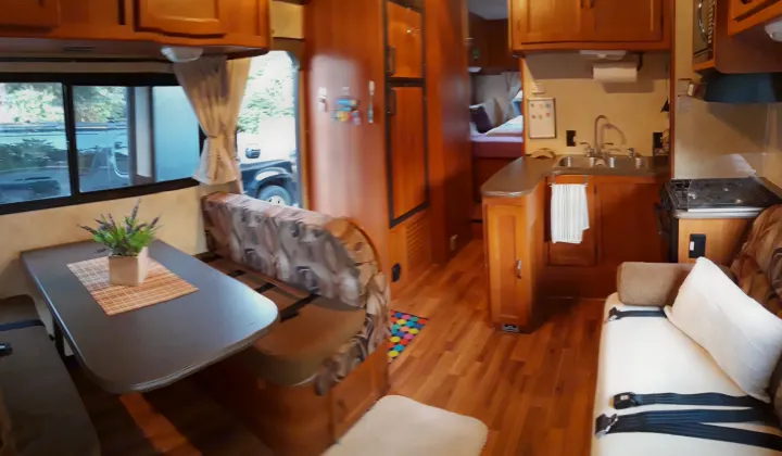 Explore this RV rental's cozy interior, featuring a well-equipped kitchen, dining booth, and comfy seating. Perfect for travels!. Coachmen Freelander 2011