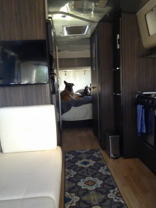 Spacious RV rental interior with a cozy pet-friendly area for a German Shepherd, showcasing modern cabinetry and comfortable seating.. Airstream International 2015