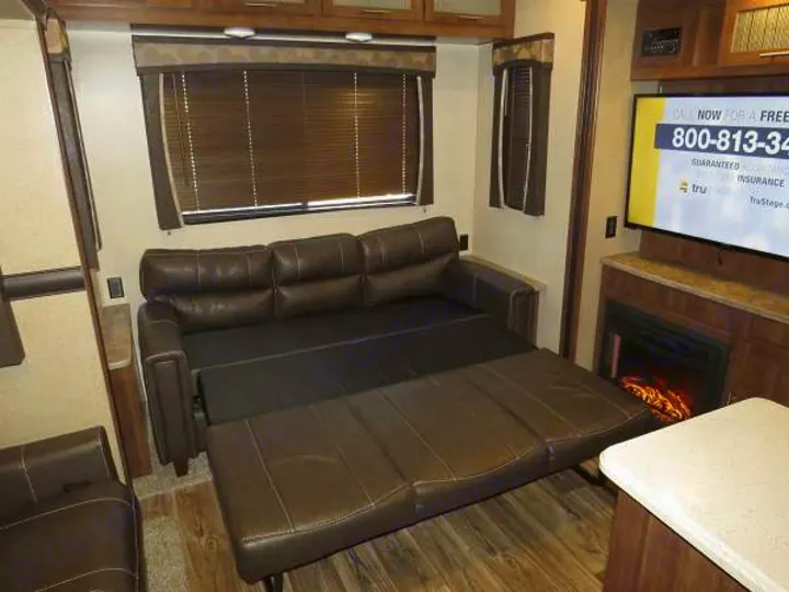 This RV rental interior boasts a comfortable convertible sofa bed, TV, and fireplace, perfect for travel.. Keystone Volante 3801MD 2018