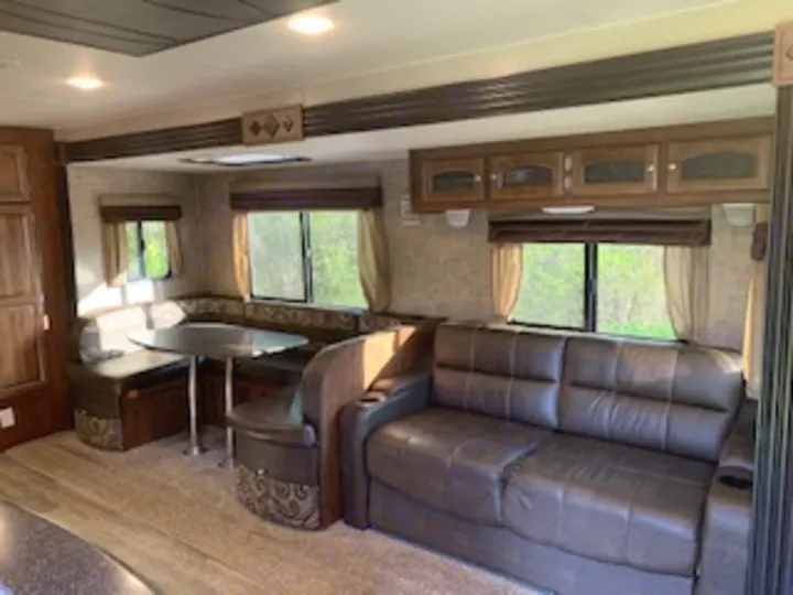 Discover this clean RV rental's inviting living area, featuring a brown sofa, U-shaped dinette, and bright windows.. Coachmen Freedom Express - Liberty Edition 2017