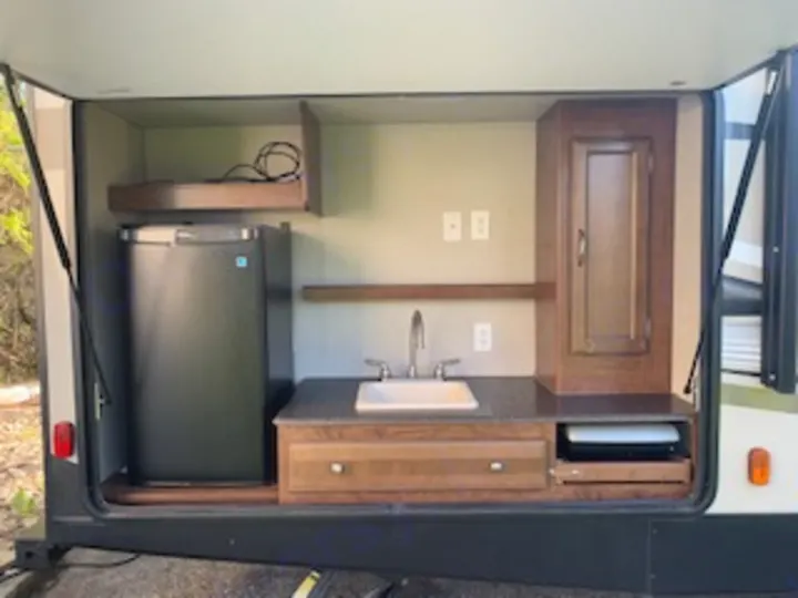 This RV rental's exterior kitchen features a mini-fridge, sink, counter, and griddle, perfect for outdoor cooking.. Coachmen Freedom Express - Liberty Edition 2017