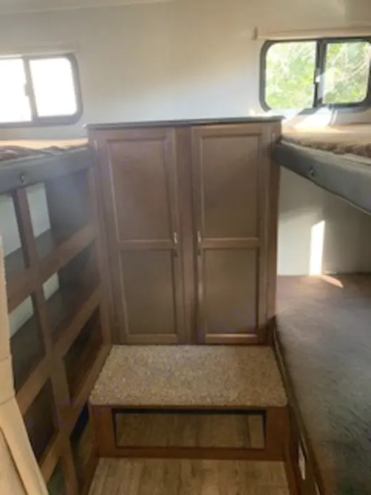 RV rental interior: features a bunk bed, dark wood cabinets for storage, open shelving below, and windows for natural light.. Coachmen Freedom Express - Liberty Edition 2017