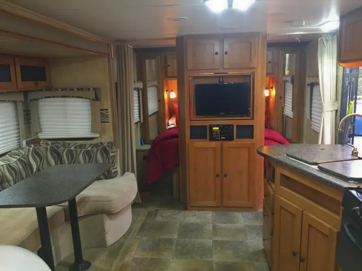 Uncrowded main area with kitchen along one side, across from a long slide that is an entire booth couch and two tables.. Cruiser Rv Corp Shadow Cruiser 2014