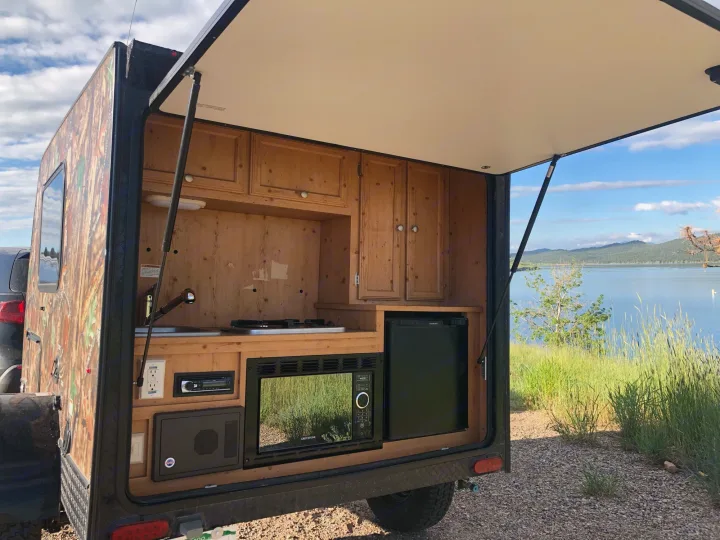 Enjoy lakeside camping with this rv rental's outdoor kitchen, featuring a microwave, fridge, and stove.. Sunset Park & Rv Inc. Other 2017