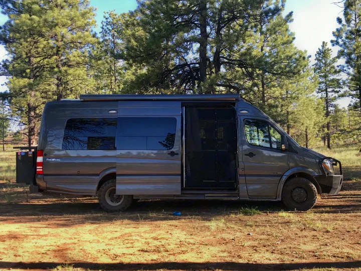 Adventure awaits in this rugged Mercedes Sprinter RV rental, parked amidst towering pines on a sunny day.. Roadtrek RS E-Trek 2018