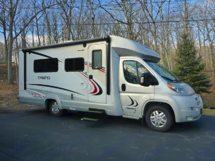 This silver & white Winnebago Trend rv rental is parked on a paved lot. Ready for adventure with striking graphics & large windows.. Winnebago Trend 2016