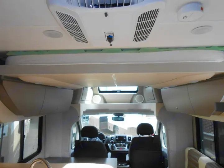 Spacious RV rental interior with an overhead sleeping area, visible front cabin, and ceiling amenities like AC vents.. Winnebago Trend 2016