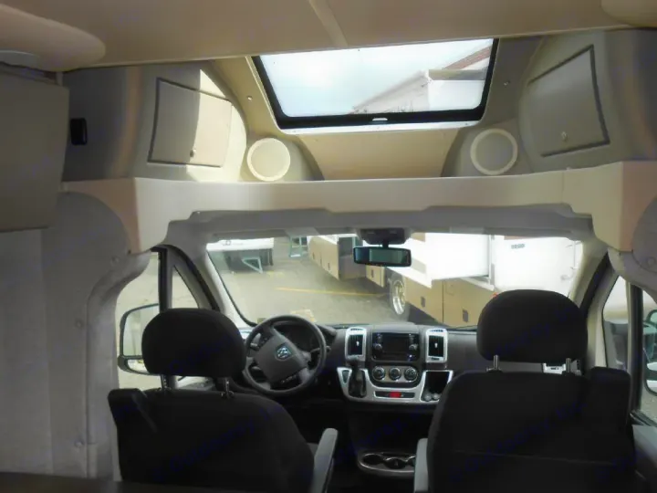 Inside an RV rental, showing the spacious cockpit with dashboard, front seats, and an overhead bunk. Ready for adventure!. Winnebago Trend 2016