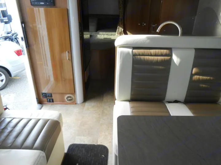 RV rental interior showing dinette seating, table, and small kitchenette with a sink.. Winnebago Trend 2016