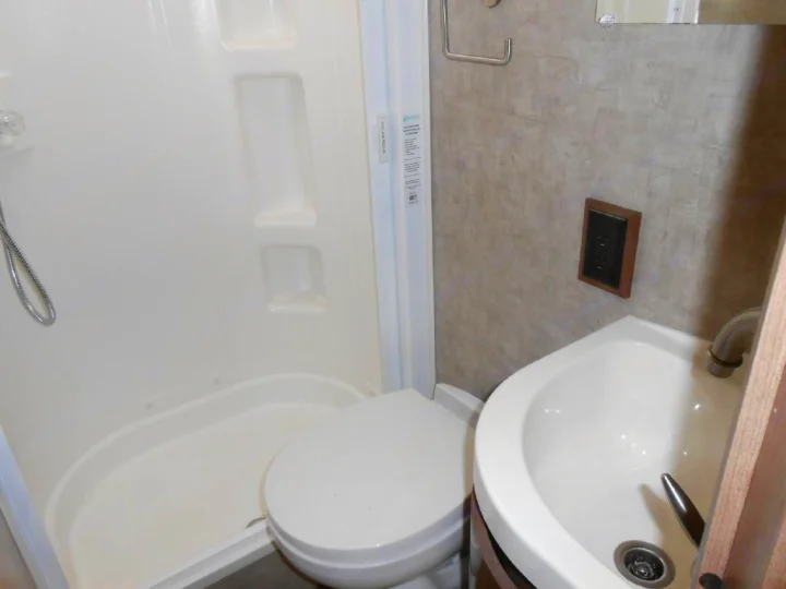 This compact RV rental bathroom provides a shower, toilet, and corner sink. Essential onboard amenities for your travels.. Winnebago Trend 2016