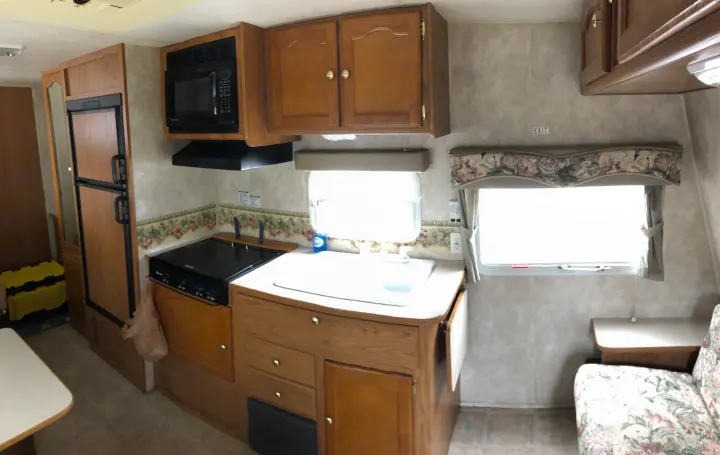 RV rental interior: Kitchen view with microwave, stove, sink, refrigerator, and wood cabinets.. Keystone Springdale 2004