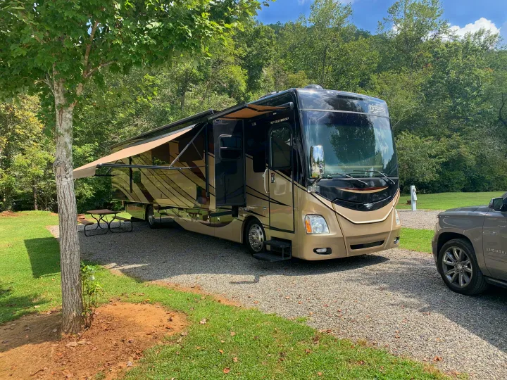 Fleetwood Discovery RV rental parked at a scenic campsite, featuring extended awnings and slide-outs for comfort.. Fleetwood Discovery 2015