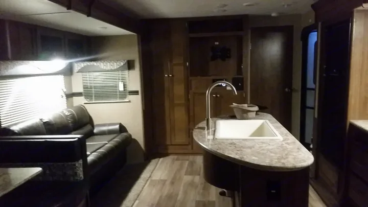 Experience comfort in this RV rental's spacious interior. Features a modern kitchen island with sink and a cozy living area.. Dutchmen Aspen Trail 2018
