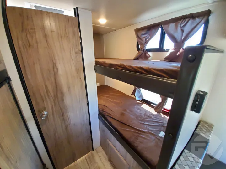 An RV rental interior showcasing practical bunk beds with brown linens and windows, ideal for family travel.. Palomino Palomini 2020
