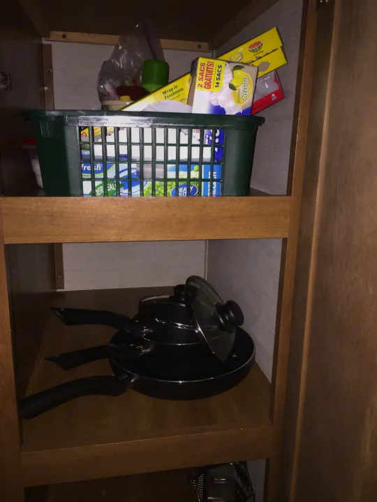 RV rental kitchen storage: stacked pots/pans, lemon-scented bags, and food wraps. Efficient RV organization.. Keystone RV Summerland Mini 2015