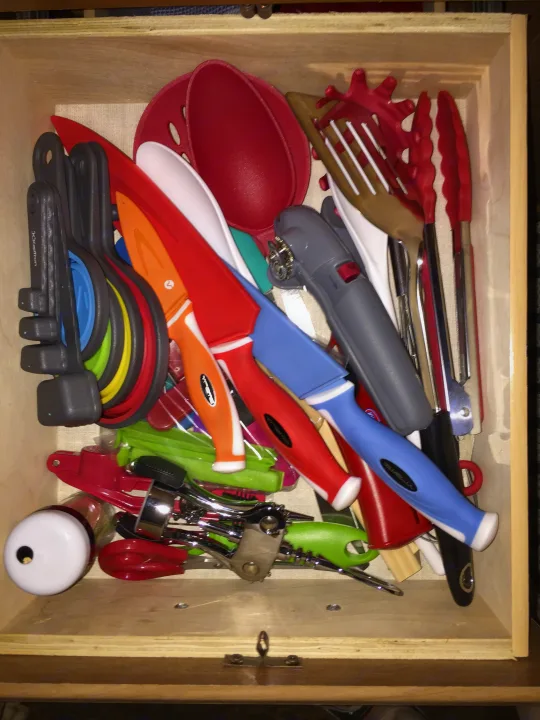 Neatly packed kitchen utensil drawer. Colorful knives, tongs, and measuring spoons, handy for any RV rental adventure.. Keystone RV Summerland Mini 2015