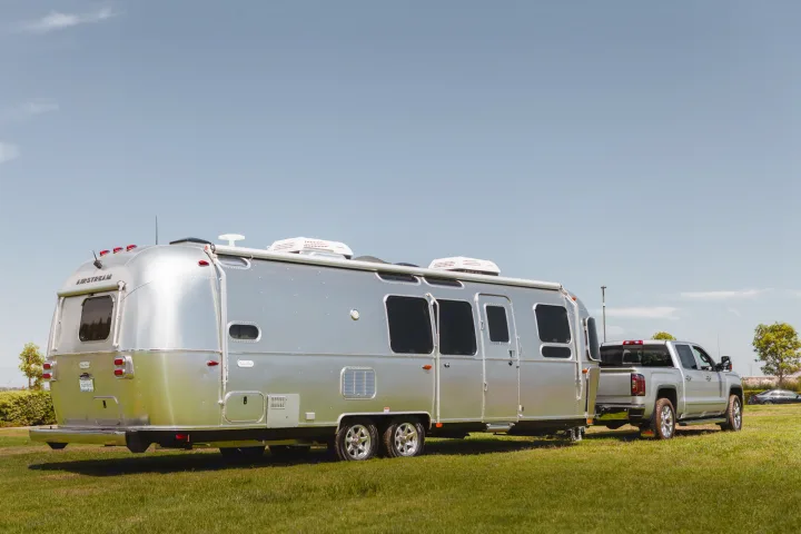 Silver Airstream travel trailer and pickup truck, ideal for your next RV rental adventure. Ready for towing & camping.. Airstream Flying Cloud 2020