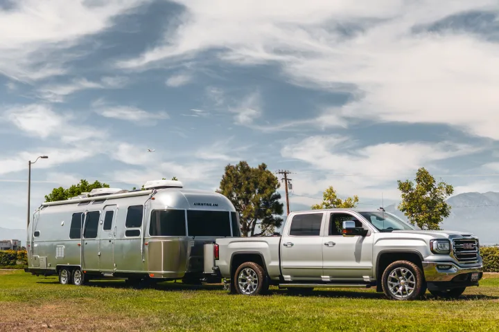 A silver Airstream RV rental is hitched to a GMC truck on a sunny day. Perfect for memorable travel trailer road trips.. Airstream Flying Cloud 2020