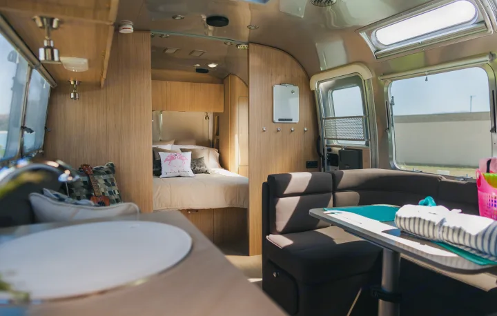 Step into this modern RV rental's interior: a cozy bedroom with a bed, plus a bright living and dining area.. Airstream Flying Cloud 2020