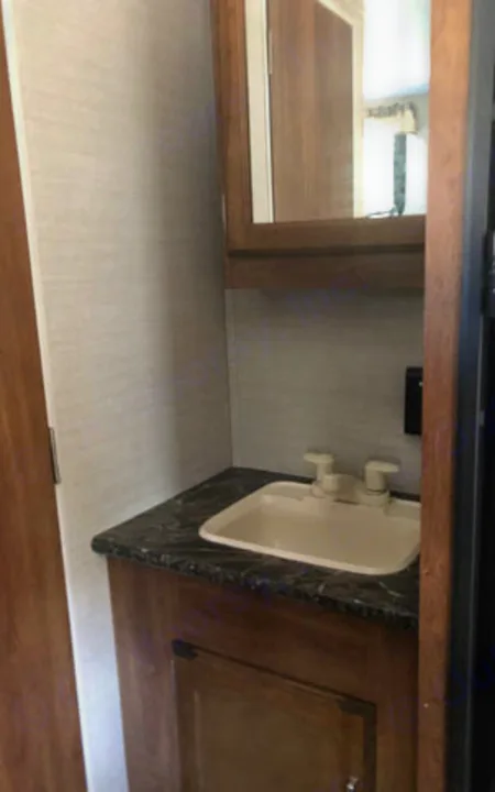 Compact RV rental bathroom features a functional vanity, sink, and mirrored medicine cabinet.. Keystone Springdale 2017