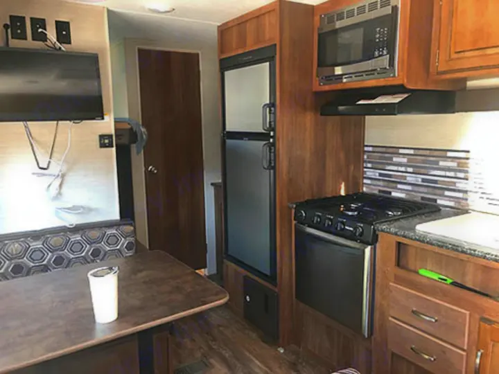 This RV rental offers a functional interior with a dinette, wall-mounted TV, and full kitchen including stove, microwave, and fridge.. Keystone Springdale 2017