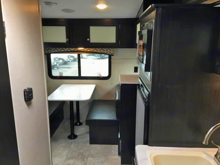 Inside this RV rental: functional dinette & kitchen setup featuring a microwave, fridge, and sink.. Venture Rv Sonic Lite SL 169VRD 2018