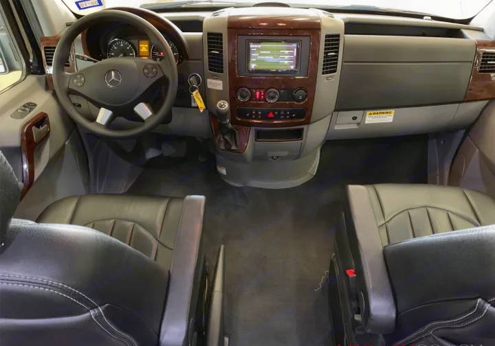 RV rental: Interior view of a Mercedes Sprinter van's cockpit, featuring dashboard, steering wheel, and front passenger seating.. Airstream Interstate 2015