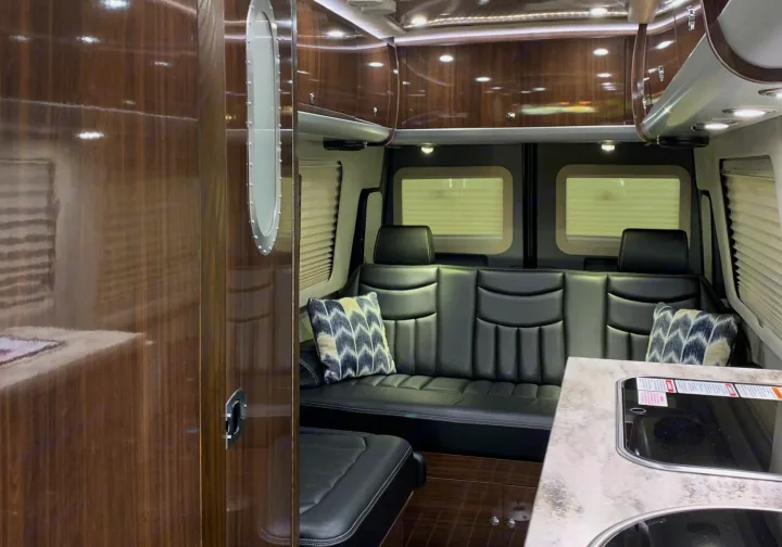 Step inside this luxury RV rental. Features include plush leather seating, polished wood finishes, and a compact galley kitchen.. Airstream Interstate 2015