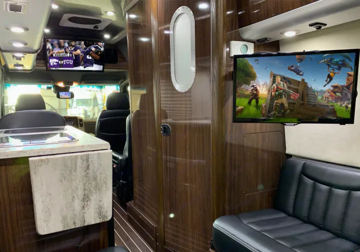 Luxury RV rental interior with dual entertainment screens: football highlights & Fortnite gaming for an ultimate road trip.. Airstream Interstate 2015