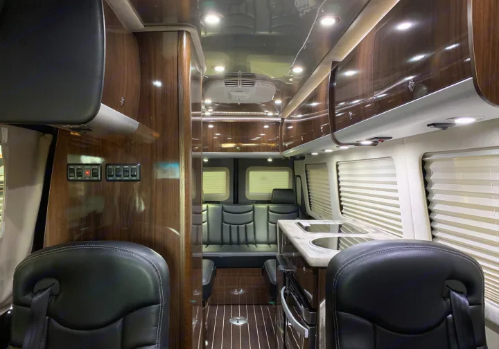Experience a luxury RV rental. This elegant camper van interior features a modern kitchenette, rich wood, and comfy seating.. Airstream Interstate 2015