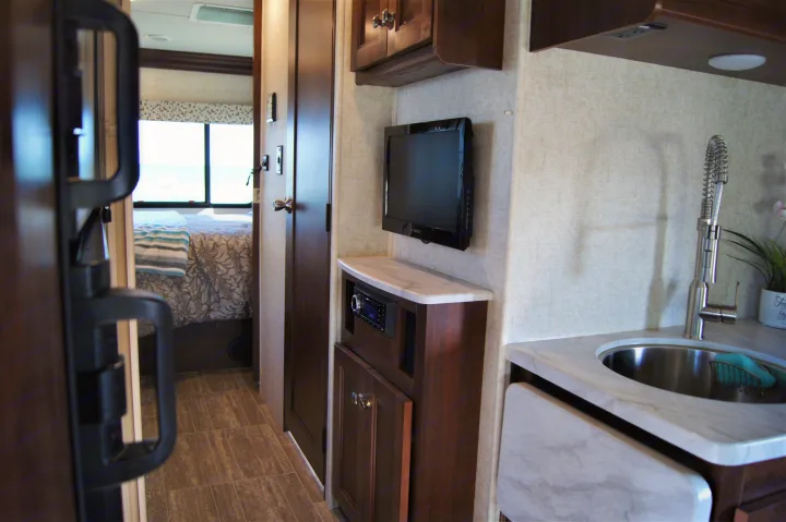 RV rental interior showcasing a bedroom, kitchenette with sink, and entertainment center. Ready for your travels.. Other Other 2019
