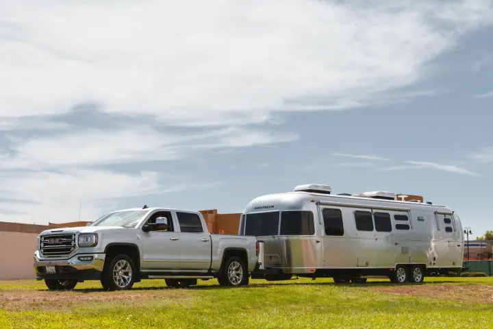 A sleek silver GMC truck and Airstream travel trailer RV rental, ready for an outdoor adventure on a sunny day.. Airstream Flying Cloud 2020