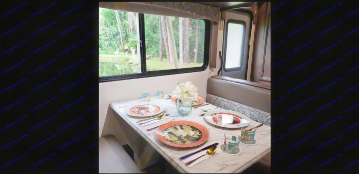 Scenic RV rental interior: dining table set with unique plates, overlooking a tranquil pond and trees outside.. Coachmen Freelander BH31 2019