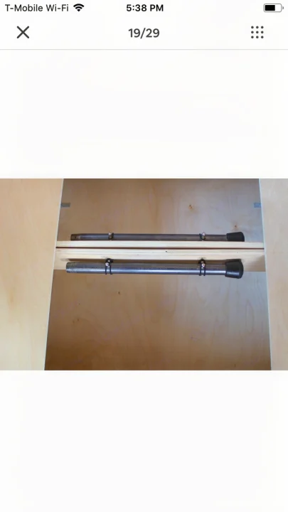 An RV rental interior features two metal rods with end caps, secured by zip ties to wood shelving, useful for organization or curtains.. ram promaster city 2016