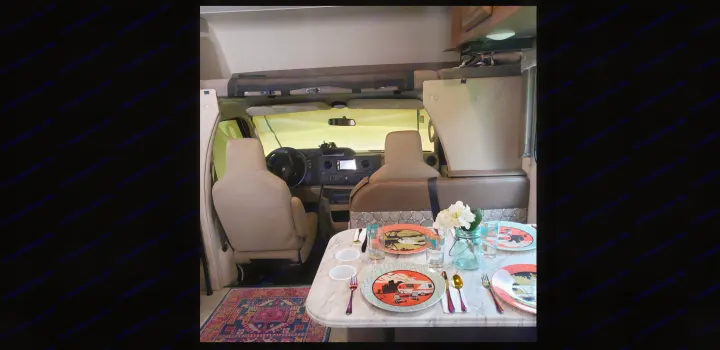 Inside an RV rental: a detailed view from the dining table towards the driver's cockpit and overhead bunk area.. Coachmen Freelander BH31 2019