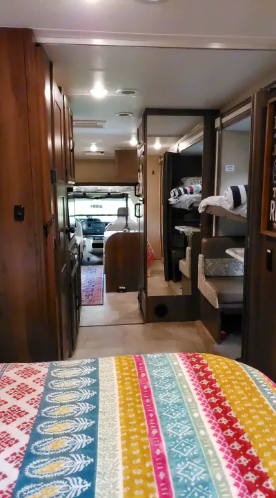 Spacious RV rental interior featuring a hallway, bunk beds, dinette, and cockpit view, providing comfort for travel.. Coachmen Freelander BH31 2019