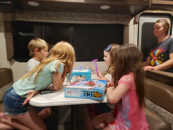 Family enjoys a board game ("Don't Break the Ice") inside their cozy RV rental, with kids gathered at the table.. Coachmen Freelander BH31 2019