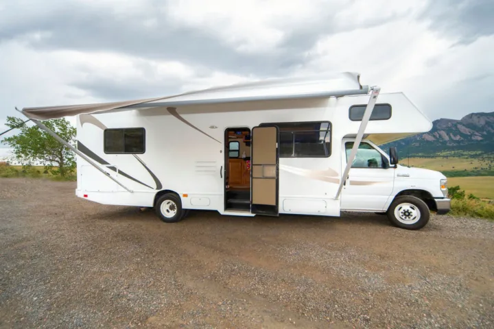White RV rental with awning extended on gravel, mountains in background. Perfect for travel & adventure.. Other Other 2015