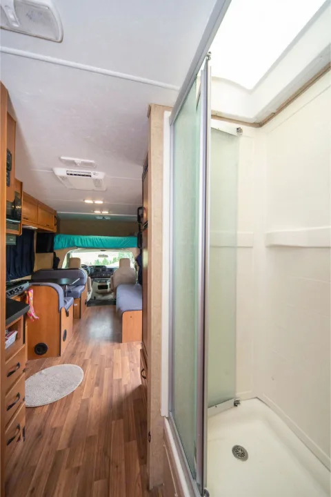 Spacious RV rental interior featuring a shower, kitchenette, living area, and overhead bed for comfortable travel.. Other Other 2015