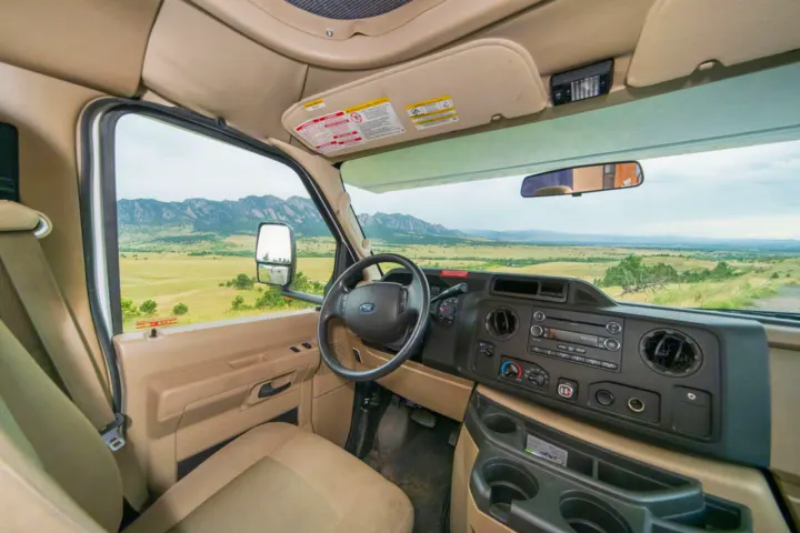 Inside an **RV rental**: Cockpit view with dashboard, steering wheel, and a vast landscape of mountains and fields outside.. Other Other 2015