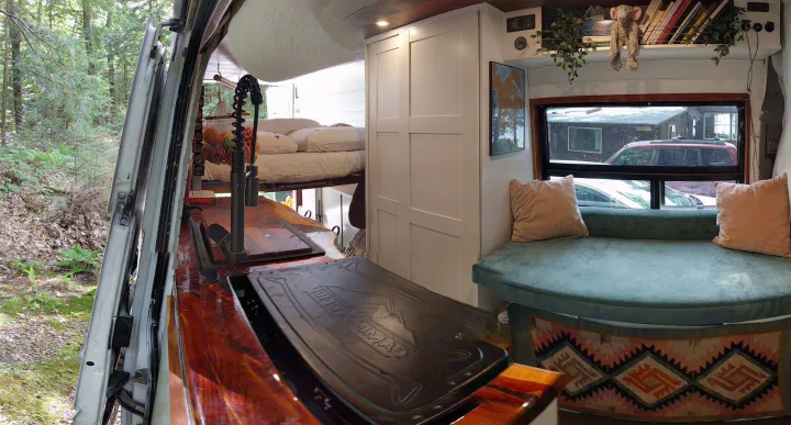 Modern rv rental interior: kitchen, raised bed, and curved lounge with window views.. Mercedes-Benz Sprinter 2005