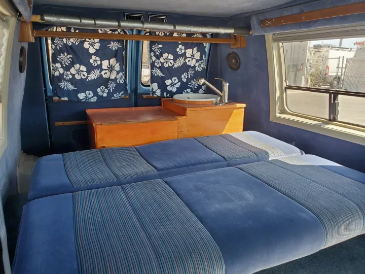 Cozy RV rental interior: blue seating/beds, sink, and flowered curtains. Ready for adventure.. Chevrolet Other 1989