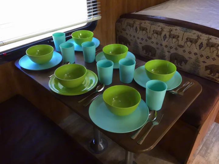 Vibrant green and blue dishware set up on a dining table inside an RV rental.. Keystone Hideout 2016