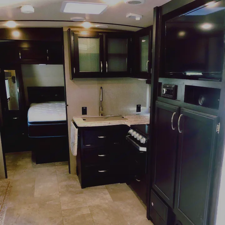 Spacious RV rental interior showcasing a modern kitchen, comfortable bedroom, and built-in entertainment system.. Grand Design Imagine 2019