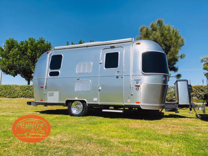 Shiny Airstream travel trailer RV rental on green grass under a clear blue sky. Perfect for your next adventure!. Airstream 19 Bambi International 2012