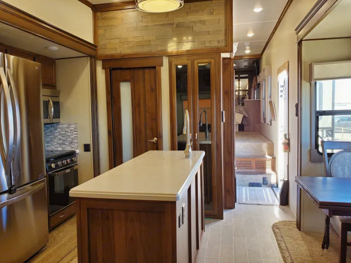 This RV rental features a full kitchen with stainless steel appliances, a large island, and a dining area, all with elegant wood finishes.. Palomino Columbus 2019