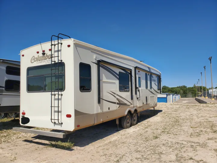 Large white & brown Columbus fifth-wheel rv rental in a sunny storage lot, ready for your next outdoor adventure.. Palomino Columbus 2019