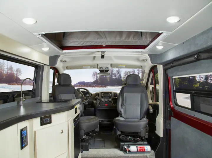 Inside a modern RV rental: driver's area, compact kitchen, and pop-top roof, ready for coastal adventures.. PleasureWay Tofino 2019