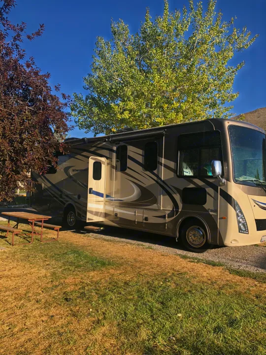 RV rental parked at a sunny site with a picnic table, ready for your camping adventures.. Thor Windsport 2018